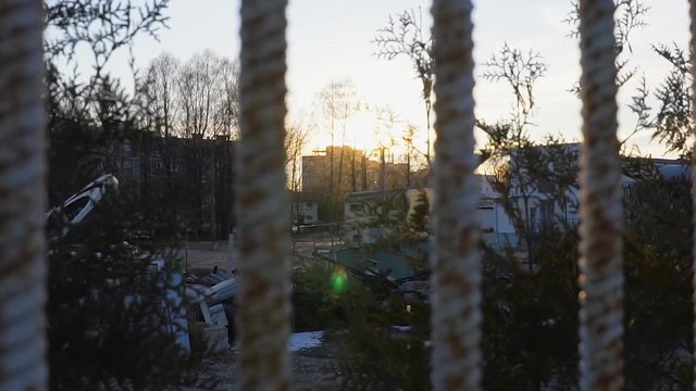 Passing on the old buildings and a metal fence at sunset in slowmotion