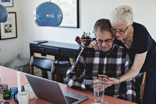 Senior couple using smartphone and laptop