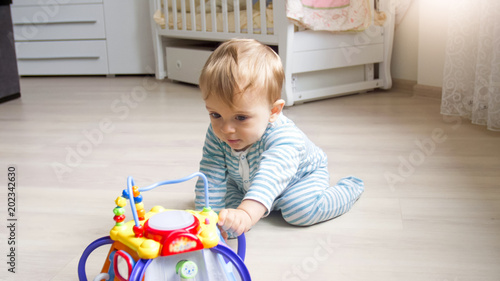 Cute 1 Year Old Toddler Boy Sitting On Floor At Bedroom And