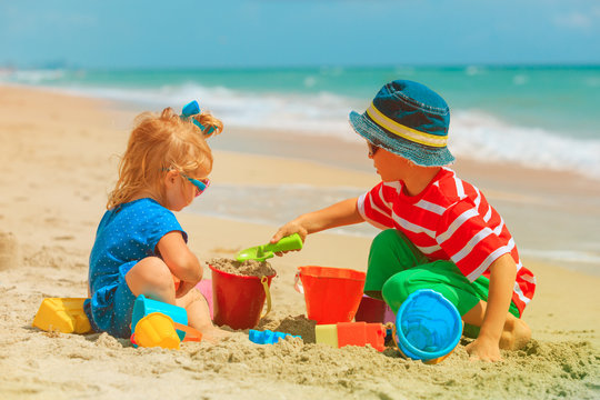 little boy and girl play with sand on beach