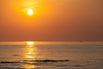 Beautiful sunrise in the morning sky creates its stunning reflection on the sea wave surface.
