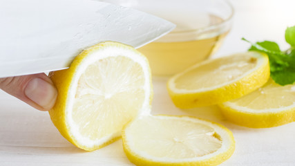 Closeup photo of sharp knife cutting fresh lemon in slices