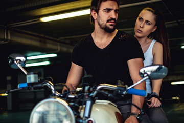 Fototapeta na wymiar Angry girlfriend talking to her biker boyfriend in a garage
