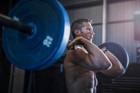 Man exercising in gym, using barbell, front squat position