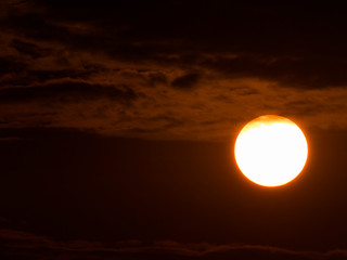 White Sun behind The Red Clouds and Sky