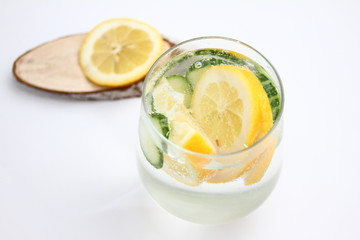 Detox flavored water with lemon and cucumber on white background with wood decoration. Healthy food concept.  Refreshing summer homemade cocktail. Copy space. No sharpen. 