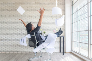 Asian businessman tossing a bunch of papers celebrating the end of his work and success report. He...