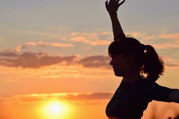 Young woman in sunset light, success, happiness, fitness concept