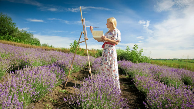 Yougn blonde woman painting lavender field at sunny morning