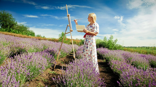 Young blonde woman drawing blooming lavender field at morning