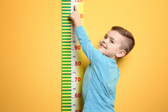 Little boy measuring his height on color background