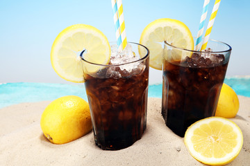 Softdrink with ice cubes, lemon and straw in glass.