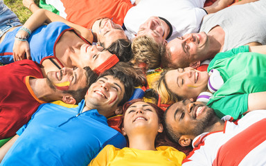 Happy friend group lying on meadow after world soccer event - Friendship concept with young people...