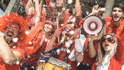Vrienden voetbalsupporter fans juichen met confetti kijken naar voetbalwedstrijd evenement in stadion - jongeren groep met rode t-shirts met opgewonden plezier op sport wereldkampioenschap concept