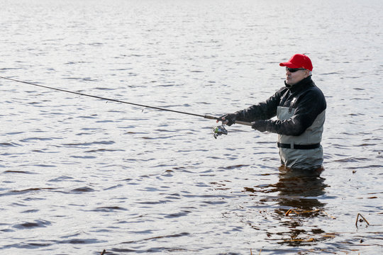 Fishermen Spin Fishing Using Chest Waders To Stay Dry.