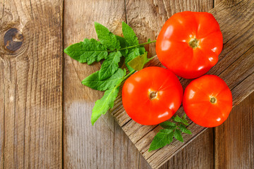 Fresh tomatoes with leaves on an old wooden table.