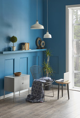 blue living room corner with home furnitures black chair white lamp and ornaments.