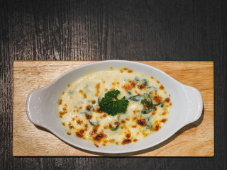 Closeup Shot at The Creamed Spinach Casserole or Baked Spinach with Cheese in A White Dish on  A Dark Background.