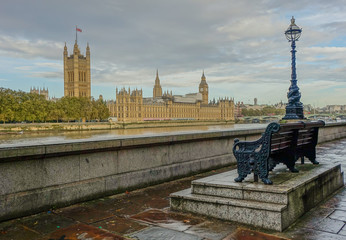 Westminster, London, United Kingdom - October 17, 2016: View of Big Ben and Houses of Parliament from the opposite bank of the Tamesis, with a bench and lamppost in the foreground