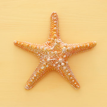 vacation and summer image with starfish over yellow wooden background.