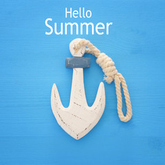 vacation and summer image with anchor over blue wooden background.