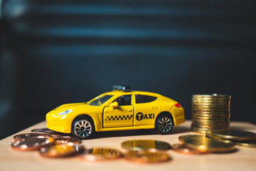 Closeup yellow taxi with golden stack coins on dark background