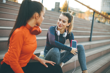 Two attractive female runner taking break after jogging outdoors