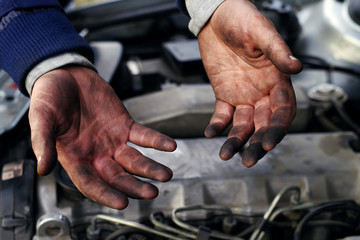 Hands of a mechanic in oil and fuel oil with a wrench during repair of the engine