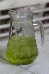 Glass pitcher of iced green tea on the table.