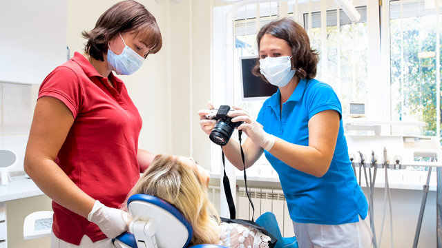 Portrait of female dentist making image of patients teeth on digital camera