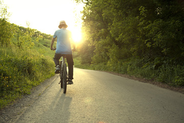 teenager riding a bicycle on the road summer sunlit