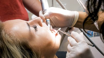 Closeup image of blonde young woman opens mouth for teeth treatment