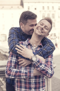 happy gay men hugging each other in the street kidding and making jokes