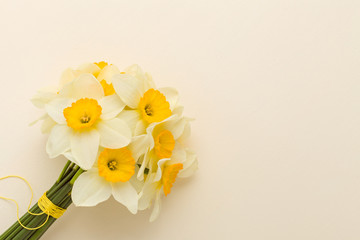 White daffodil bouquet on yellow pastel background with copy space.