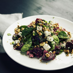 Beetroot salad with cottage cheese, baby spinach and walnuts. European cuisine. Organic food. Vegetarian appetizer. Healthy lifestyle. Simple side dish. Toned photo.