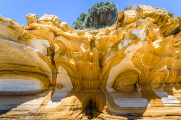 Amazing coast line called Painted Cliffs with orange yellow colored sand limestone rocks and geology structures at shore, perfect expedition on warm sunny clear day, Maria Island, Tasmania, Australia