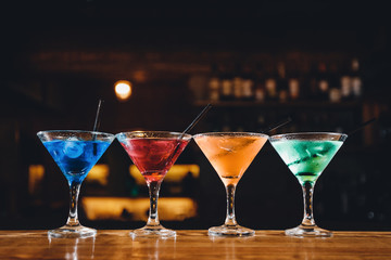 Barman mixes cocktail show with colorful alcoholic cocktails at bar counter.