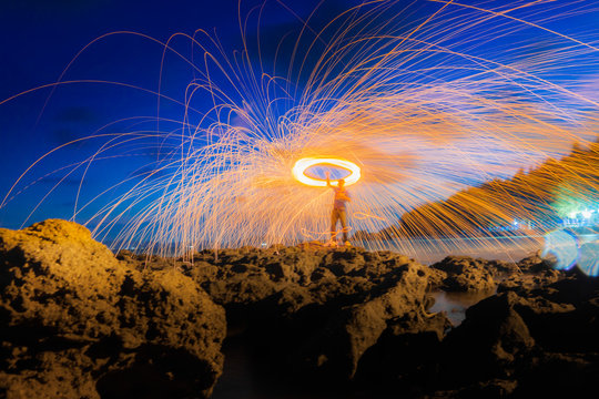 A Ring Of Fire Spinning Steel Wool On The Rock And Beach, Showers Of Hot Glowing Sparks From Spinning Steel Wool On The Rock And Beach.