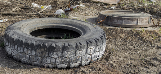 Old tire and sewer hatch. Manhole cover. Old tire on the roadside. Abstract background