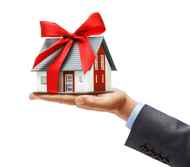 Men's hand in suit holding house with red ribbon isolated on white background. Close up. High...