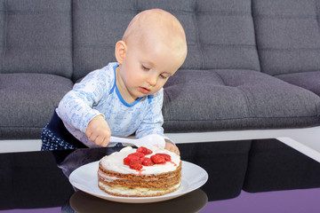 First birthday celebration of a little boy. Little boy eating birthday cake with a spoon, happy birthday. Toddler at table with cake.