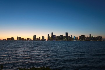 Fototapeta na wymiar City of Miami Skyline After Dusk in the Magic Hour of Twilight with Buildings Illuminated Next to the Rickenbacher Causeway in Key Biscayne, Florida