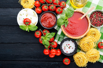 Ingredients for cooking - tomato sauce, pasta, tomatoes, garlic, olive oil on the old wooden background. top view.
