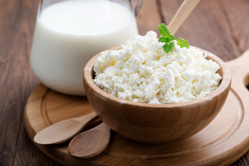 Homemade cottage cheese in a wooden bowl on dark wooden background.  - obrazy, fototapety, plakaty