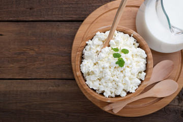 Homemade cottage cheese in a wooden bowl on dark wooden background. top view.