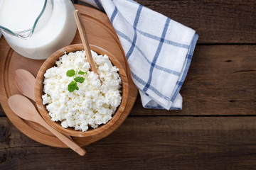 Homemade cottage cheese in a wooden bowl on dark wooden background. top view.