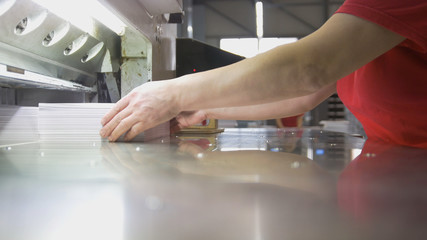 Female worker folds a stack of paper in the typography