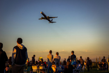 Fototapeta na wymiar People watching airplane at sunset