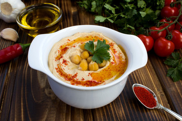 Hummus in the white plate  and vegetables on the  wooden background