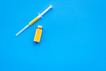 Medical injection. Syringe and bottle with remedy on blue background top view copy space